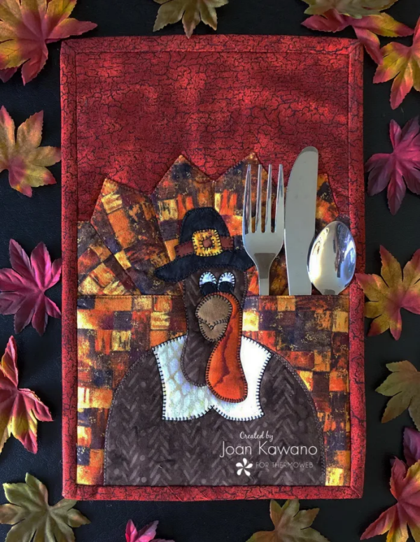 "Fabric Turkey Mug Rug with a Twist" is a Free Thanksgiving Quilted Table Pattern designed by Joan Kawano of Moosestash Quilting from Therm-O-Web!